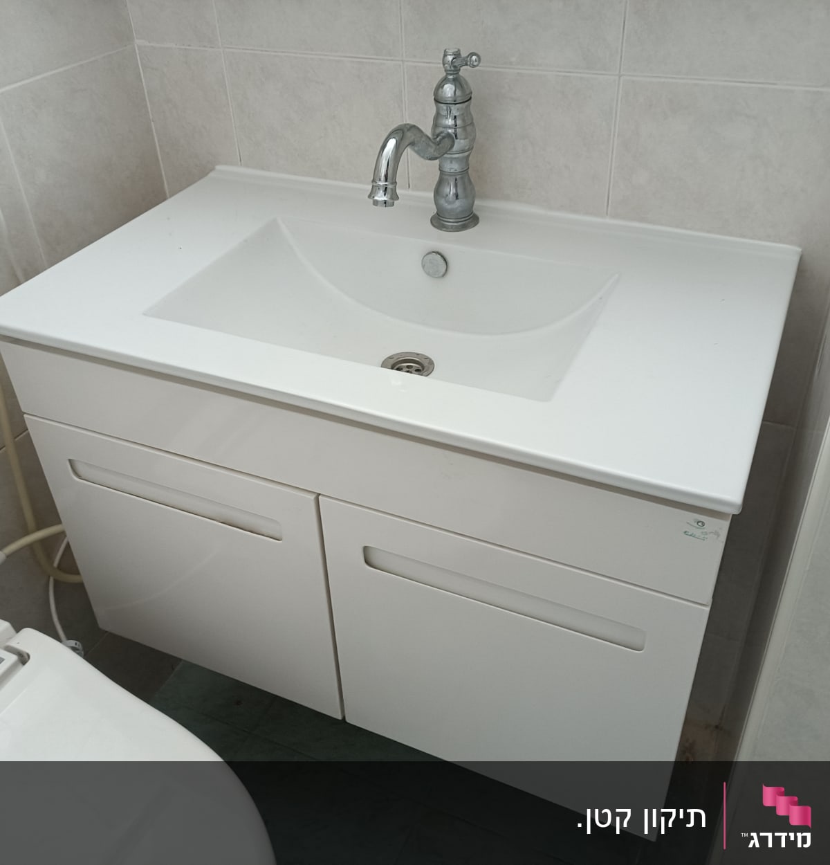 כיור לבן עם ברז מתכת בחדר אמבטיה